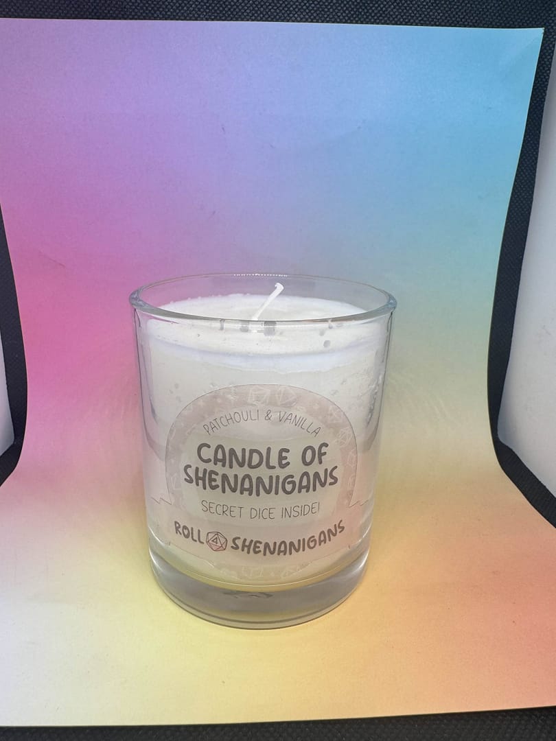 “Candle of Shenanigans Patchouli and Vanilla scented candle with secret mystery dice inside, made by Roll 4 Shenanigans, displayed against a pastel gradient background.”